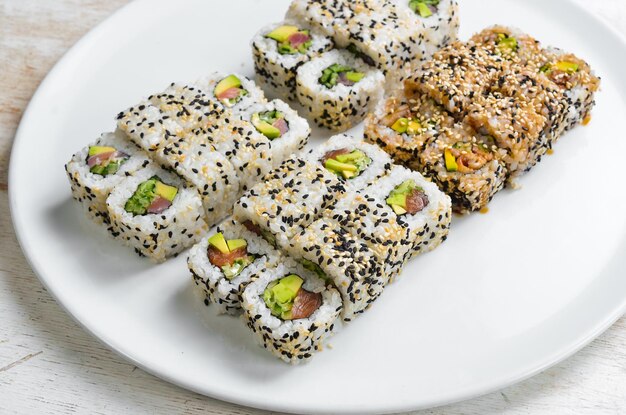 Traditionele sushi rolt en maki met sesam, avocado en vis Japans eten Bovenaanzicht op een witte achtergrond