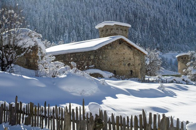 Traditionele Svan torens en huizen omgeven door besneeuwde bossen en bergen van de Kaukasus Svaneti Georgia