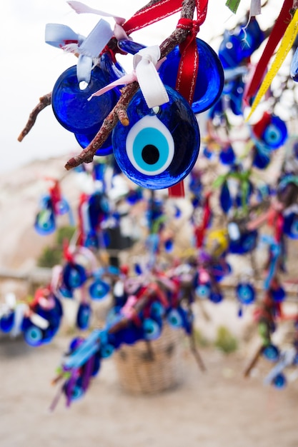 Traditionele Turkse amulet Nazar blauw oog close-up hangt aan boom met versierd met kleurrijke linten