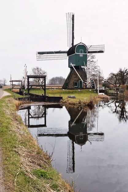 Foto traditionele windmolen met reflectie op het kanaal tegen een heldere lucht