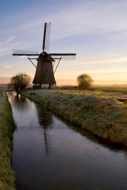 Foto traditionele windmolen op het veld tegen de hemel bij zonsondergang