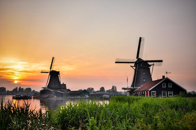 Traditionele windmolens bij de rivier tegen de hemel bij zonsondergang