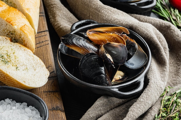 Traditionele zeevruchten mosselen in wijnsaus en stokbrood toast op zwarte houten tafel achtergrond