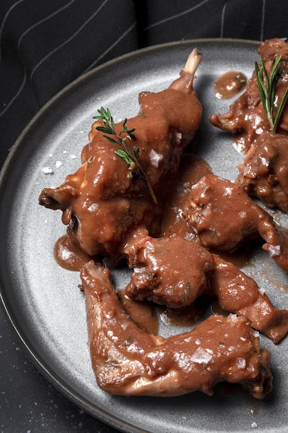 Traditionele zelfgemaakte stoofpot van konijnenvlees met rode wijnsaus met aromatische kruiden op een zwarte achtergrond