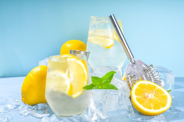 Traditionele zomer koude verfrissende cocktail limonade, met schijfjes citroen en veel gemalen ijs en bevroren sokkels op blauwe achtergrond