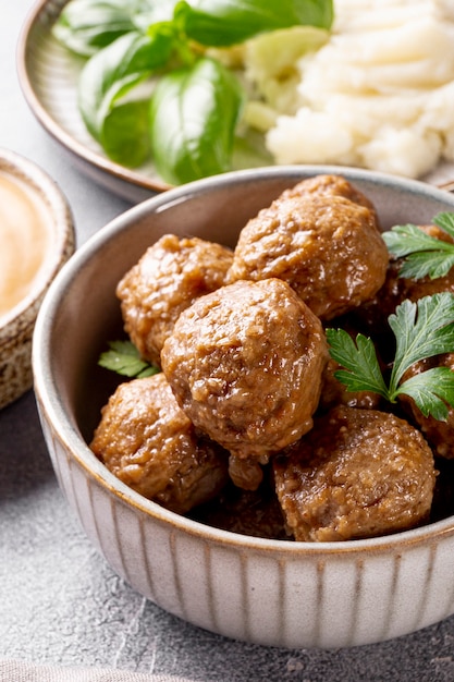 Foto traditionele zweedse gehaktballen met romige saus en aardappelpuree op grijze tafel close-up verticaal