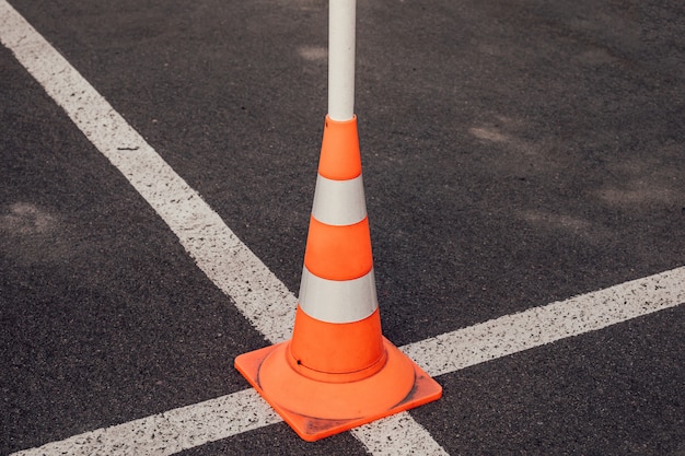 Traffic cone at the intersection of the white lines of road markings.