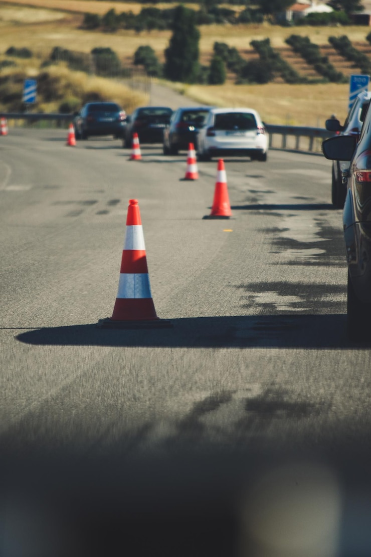 Photo traffic cones and cars on road during sunny day