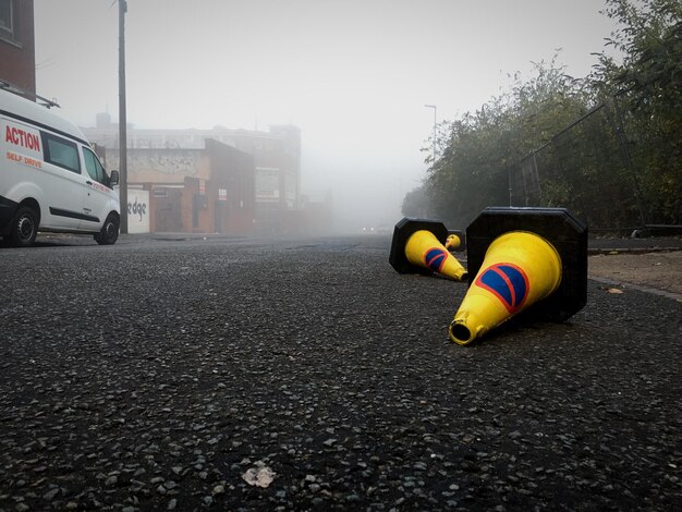 Traffic cones on road against sky during foggy weather