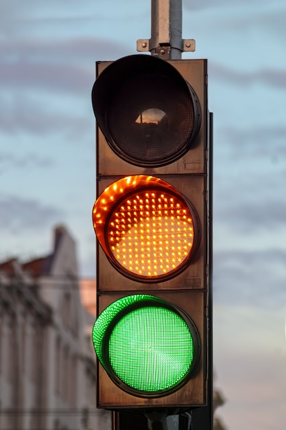 Светофор. Зеленый дорожный сигнал. Желтый светофор на проезжей части на фоне облаков. Красочный или предупреждающий знак