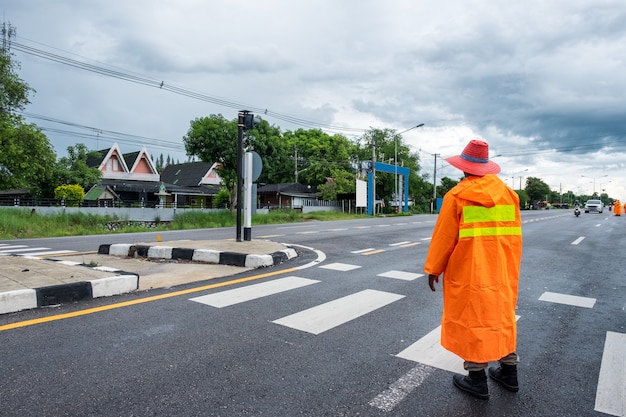 Traffic officer wearing orange raincost with control and directing traffic in countryside