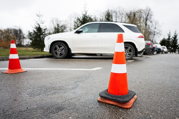 Traffic orange cones standing on a street along the parking cars