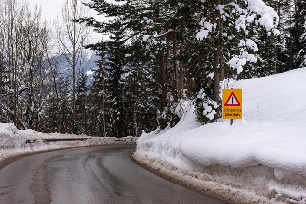 Foto segnale stradale di avvertimento servizi invernali schladming strada coperta di neve montagne alberi strada