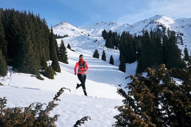 Trail runner vrouw loopt in de winter bergen trail op sneeuw