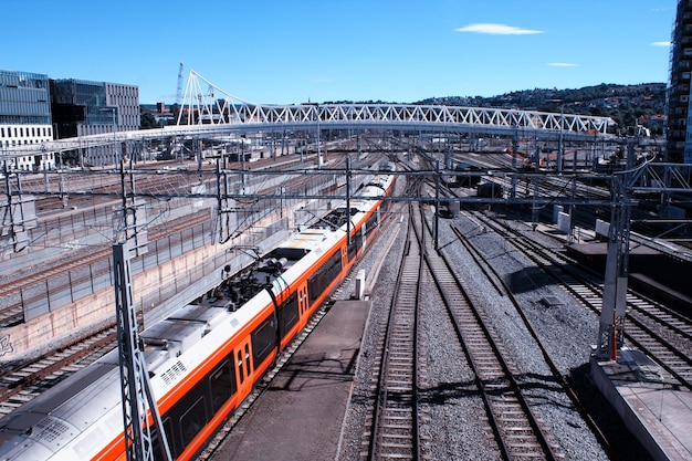 Train leaves the train station in Oslo with modern buildings