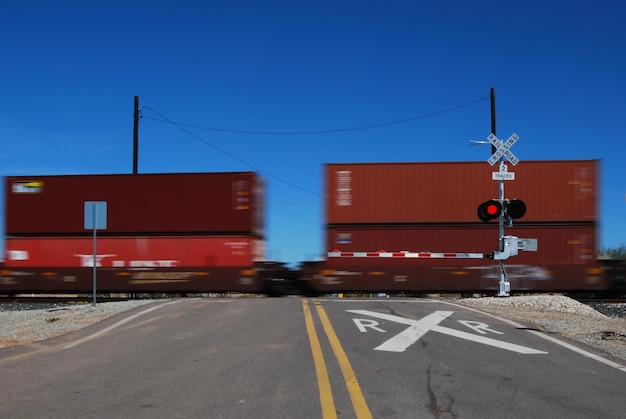 Photo train passing by railroad crossing against clear blue sky