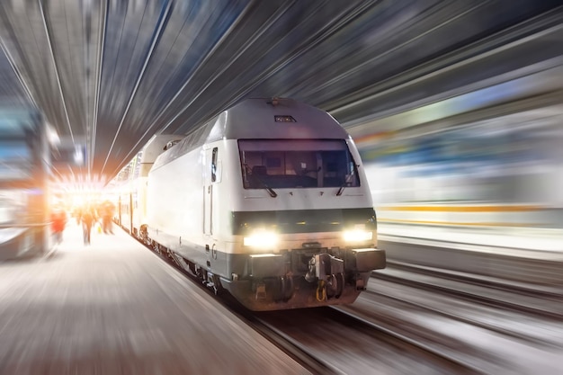 Train rides at high speed at the railway station in the night city.