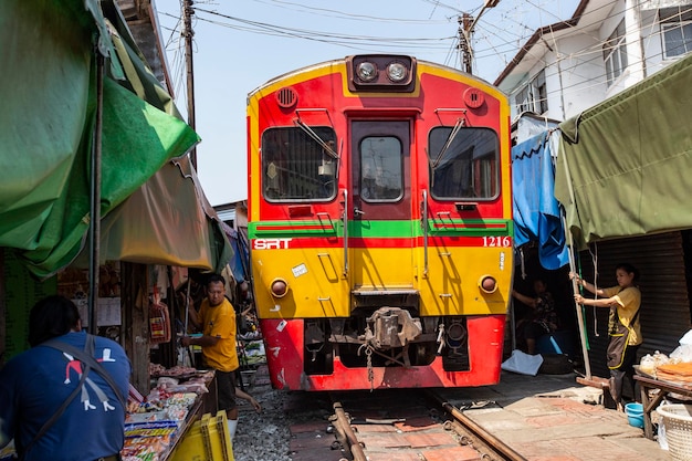 Train running through Maeklong railway market, Thailand