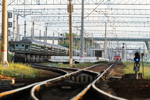 日没時の線路と背景の通勤電車の駅のプラットフォーム