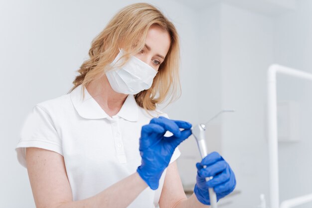 Trained excellent local doctor wearing clean sterile while checking and maintaining tools she using in her work