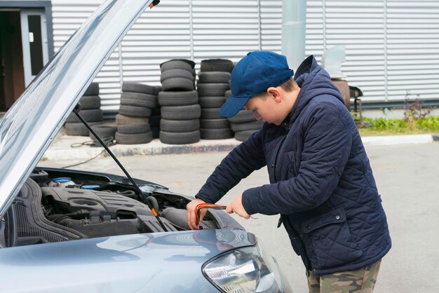 Trainee auto mechanic works in a garage outdoors Automobile Repair Service Concept