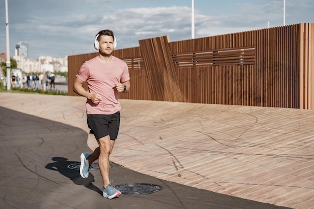 Trainen in de stad met een koptelefoon Loopschoenen volledige hoogte Runner is een jonge man