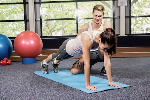 Trainer assisting woman with push ups