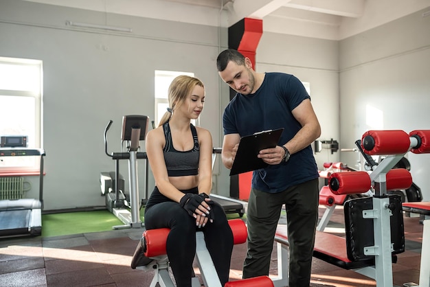 The trainer assists with female client doing workout in the gym exercise lifestyle