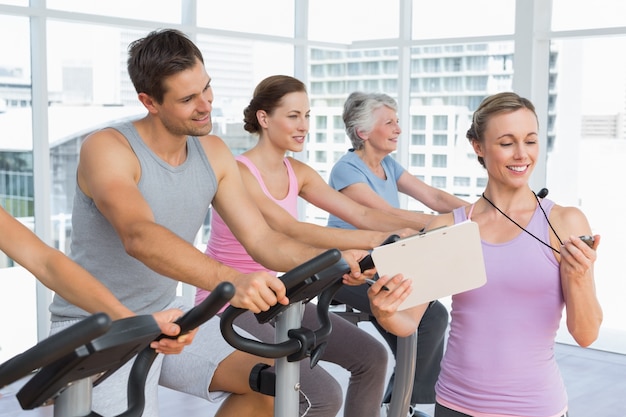 Trainer besides people working out at spinning class