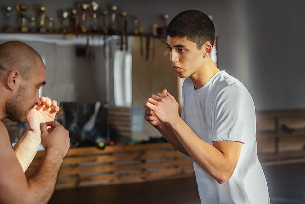 Тренер и боксер-подросток тренируются в тренажерном зале