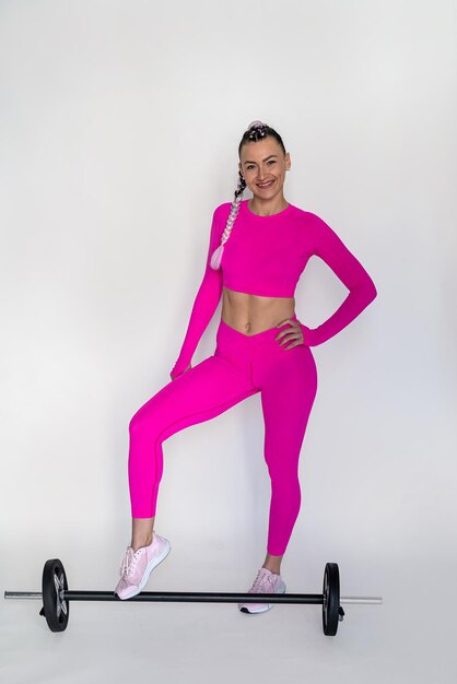 Trainer in bright crimson doing great effective exercises with barbell on studio background