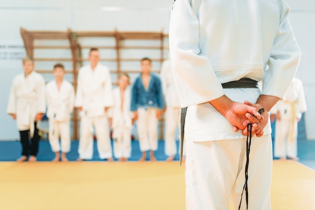 Trainer en kleine jongens in kimono, judotraining voor kinderen. Jonge vechters in de sportschool, krijgskunst voor verdediging