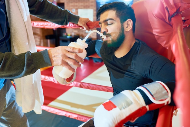 Trainer giving water to boxer