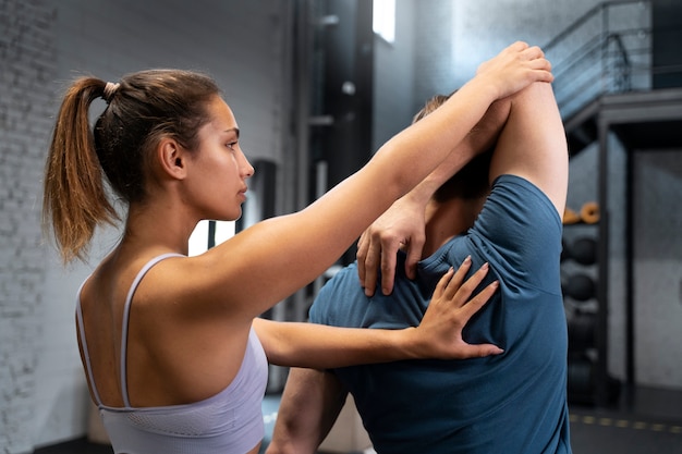 trainer helping beginner at the gym