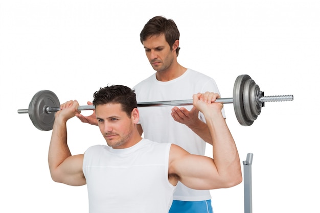 Trainer helping fit man to lift the barbell bench press