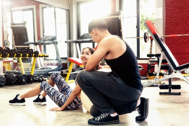 Trainer helping women push-up strength with dumbbell in a workout in the gym