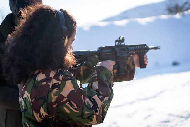 Тренер помогает молодой женщине целиться из пистолета во время боевой подготовки, фото высокого качества