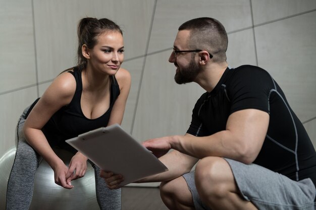 Foto trainer maakt aantekeningen terwijl de vrouw zit en rust