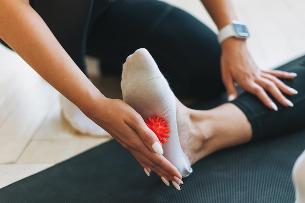 The trainer massages female feet with spiked ball prevention of the flat feet