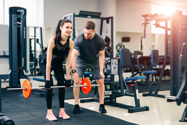 Trainer Oefeningen training "squat" en "death lift" met behulp van de halter met vrouwelijke cliënt