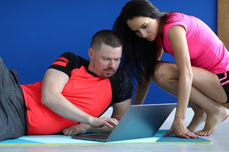 Photo trainer shows exercises to student on laptop.