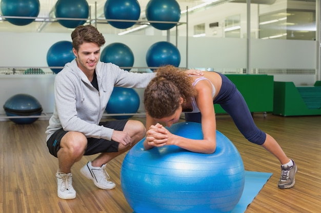 Trainer watching his client using exercise ball