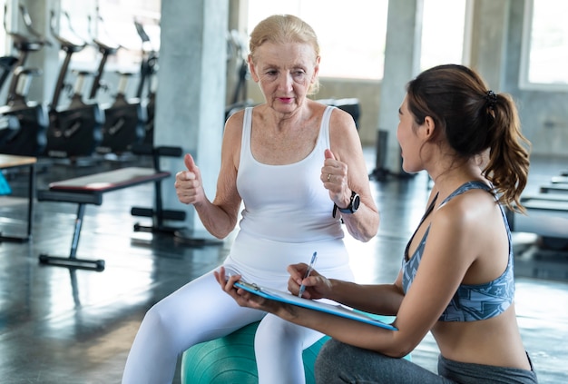 Trainer with senior woman exercise in gym. elderly healthy lifestyle and workout concept