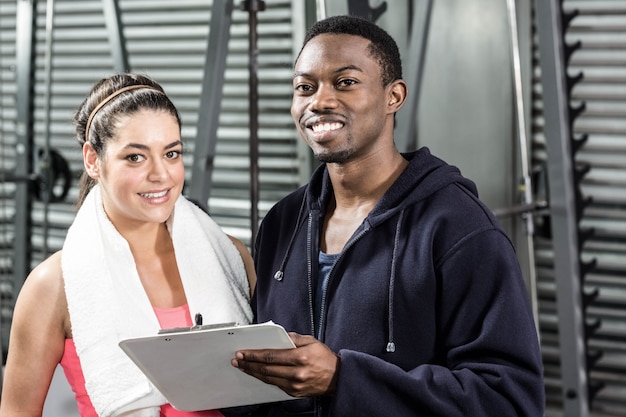 Trainer and woman looking at workout plan at  gym