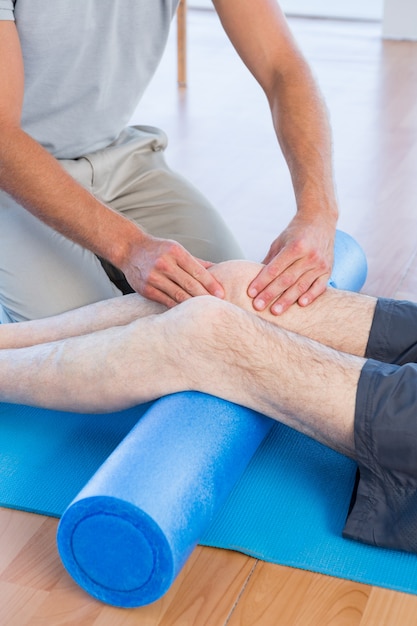 Trainer working with man on exercise mat 