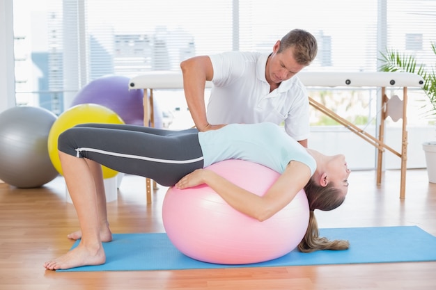 Trainer working with woman on exercise ball