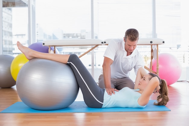 Trainer working with woman on exercise mat 