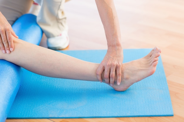 Trainer working with woman on exercise mat