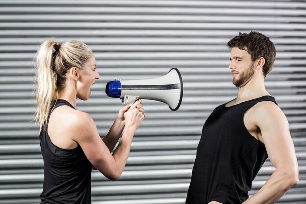 Photo trainer yelling through the megaphone at crossfit gym