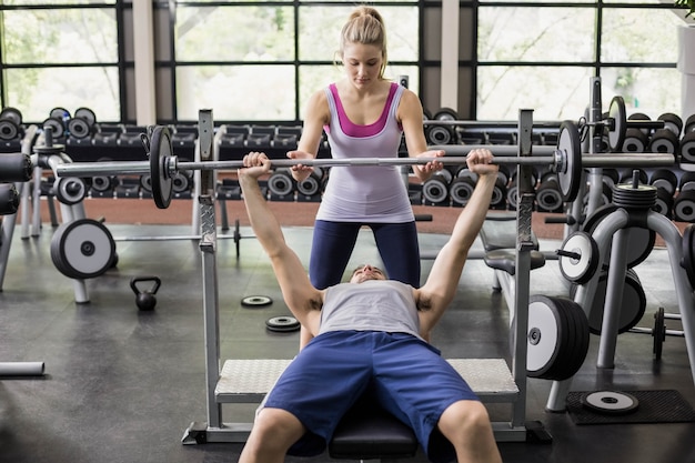 Trainervrouw die de atletische mens in gymnastiek helpen